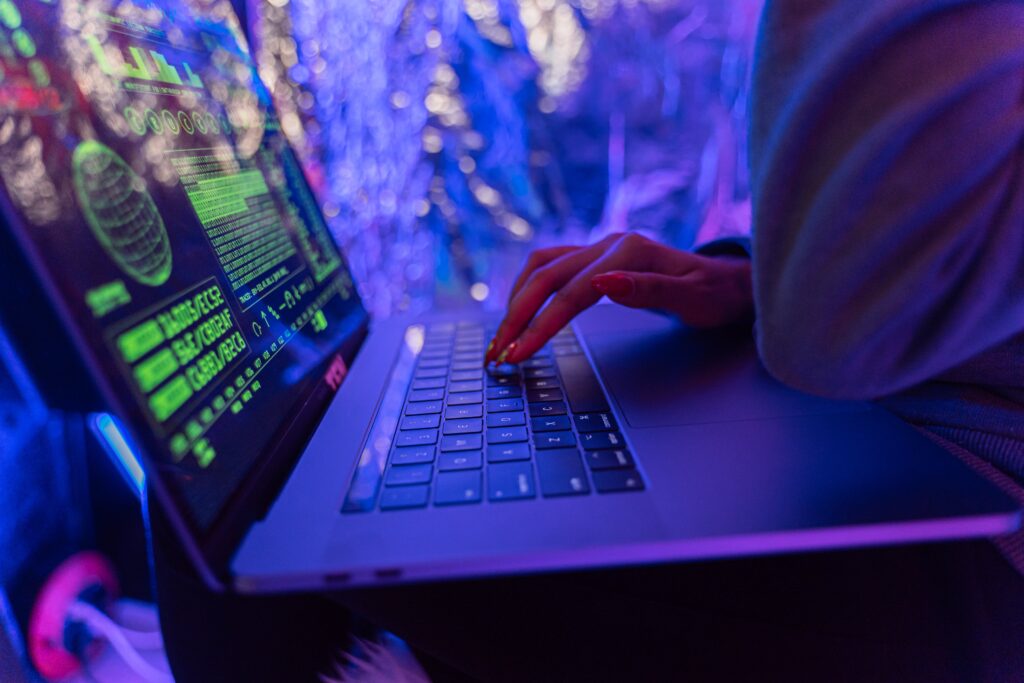 The neon purple and green Setting of a woman's hands-on macbook keyboard.